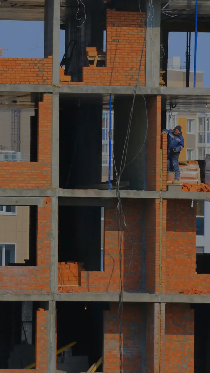 Zgrada u izgradnji: betonska konstrukcija i zidovi od crvene cigle, radnici na gornjem spratu
